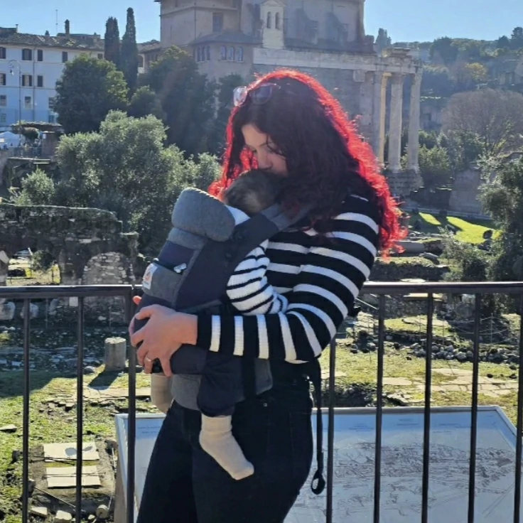 Yasmin abrazando a su hijo, que aparece de espaldas, en un mirador urbano